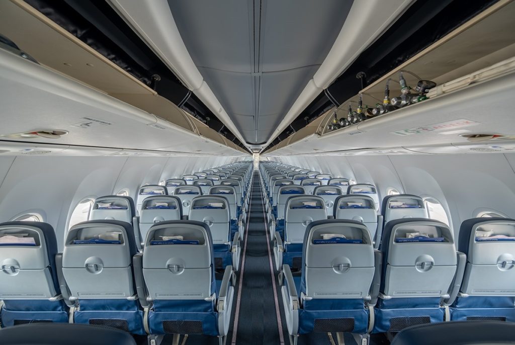 lots of economy class seats inside a 737, seen from the back of the cabin looking forward.