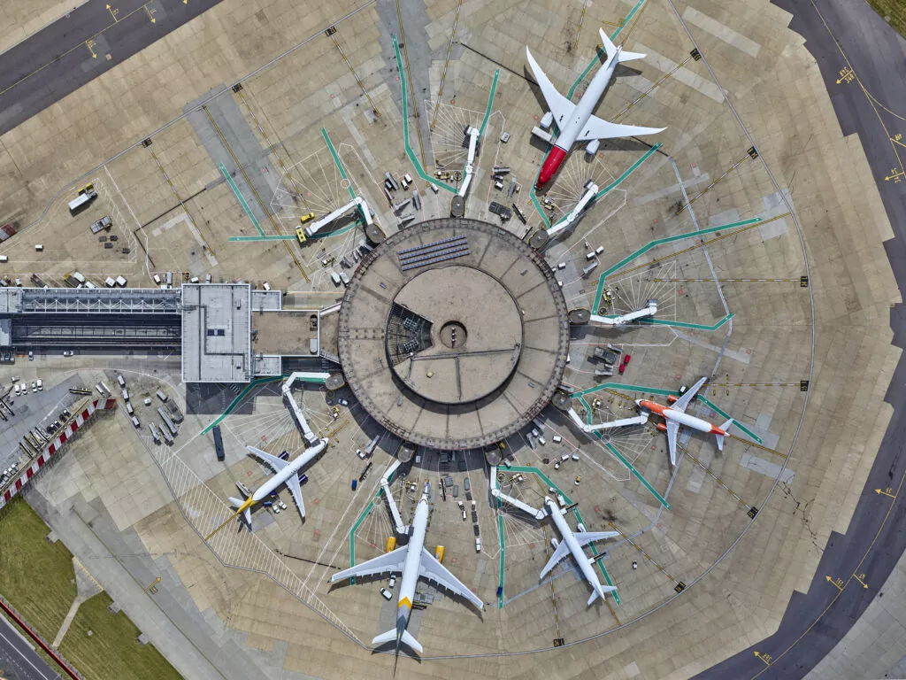 overhead view of a round airport terminal with a variety of planes parked at the gates