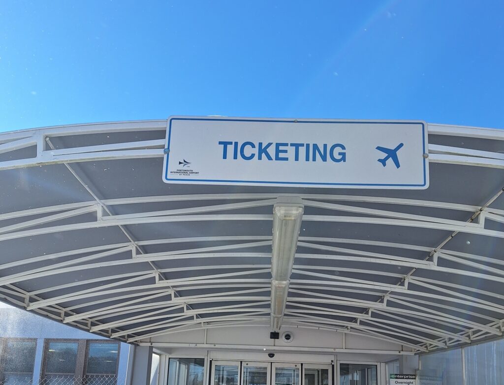 ticketing sign above an outdoor airport walkway