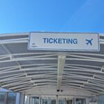 ticketing sign above an outdoor airport walkway