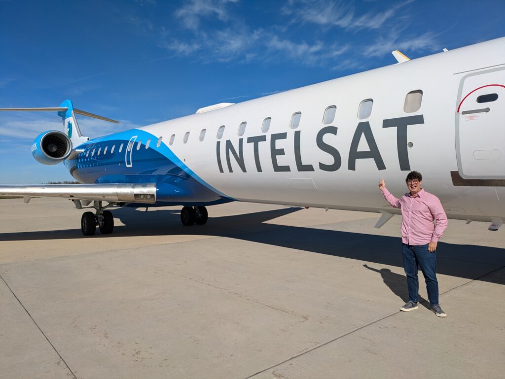 Doofus in a red shirt standing in front of a plane with