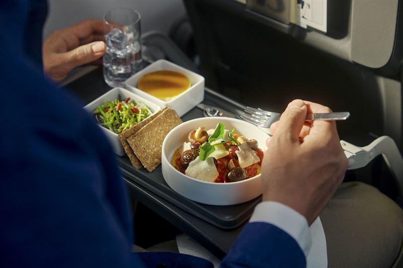 Tray table in the new SAS Business Class cabin showing a salad and sides served in real dishes.