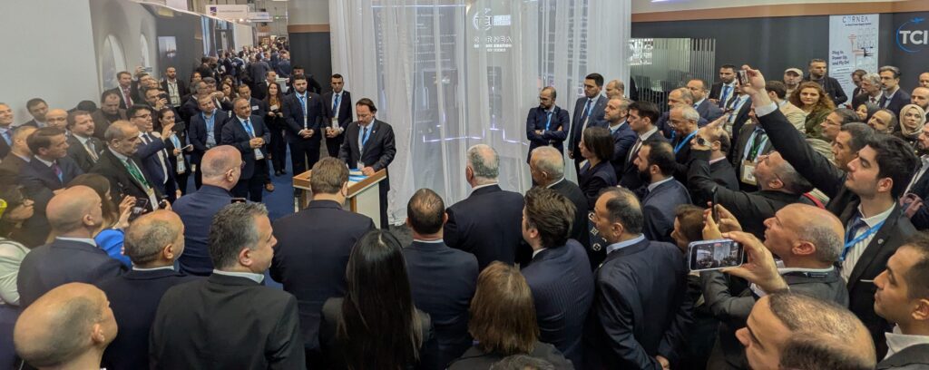A large crowd gathered around a trade show booth.
