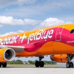 Airplane painted in bright yellow, pink, and orange reading Dunkin' and JetBlue on the side.