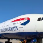 A British Airways 777 with its white fuselage and blue belly, parked on the ground at Heathrow
