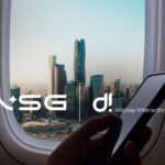 Logos for NSG and DI overlaid on an airplane window overlooking a Saudi skline