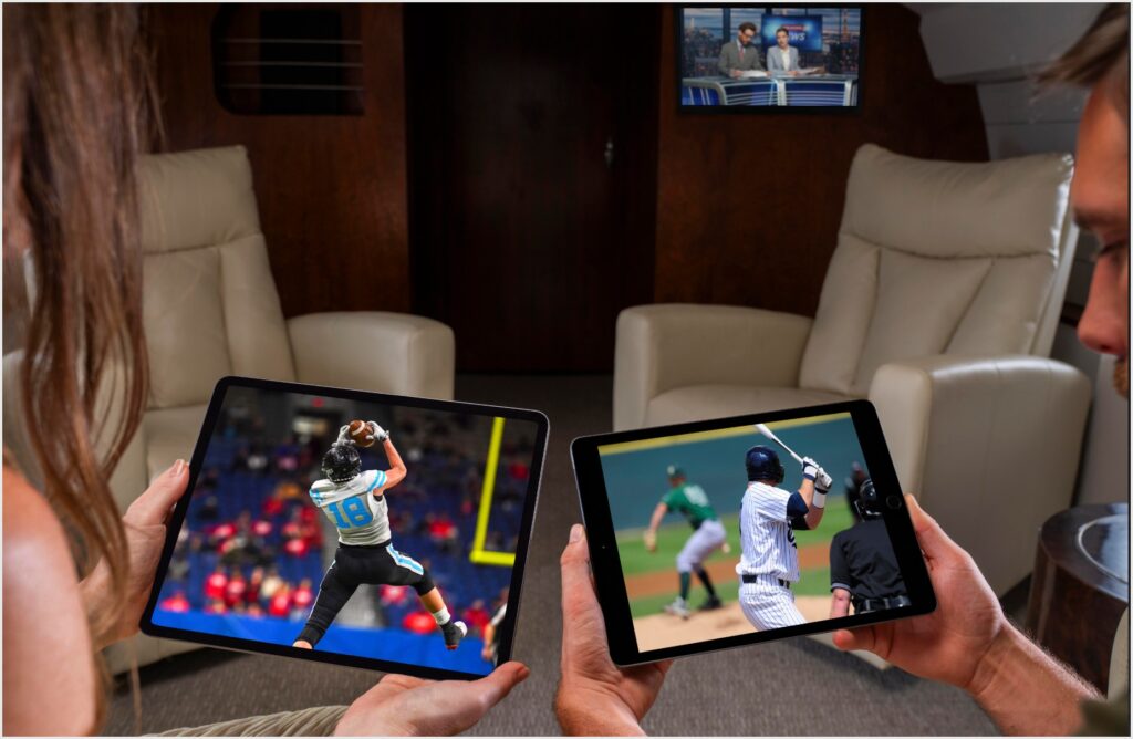 business jet passengers watching on their tablets while a screen on the bulkhead shows a different channel.