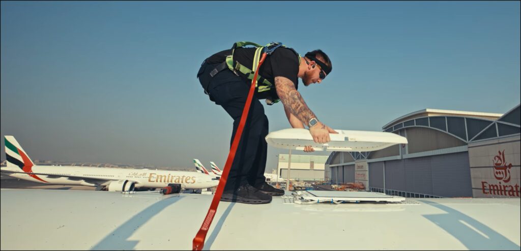 guy standing atop an Emirates 777 installing the starlink antenna faring