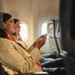 Two women using IFE and PEDs on a plane
