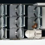 Birdseye view of a few rows in economy class on a plane, where the back row is configured with the Collins Aerospace SkyNook, an area too small for a seat replaced by a baby carrier.