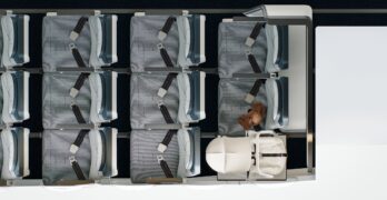Birdseye view of a few rows in economy class on a plane, where the back row is configured with the Collins Aerospace SkyNook, an area too small for a seat replaced by a baby carrier.