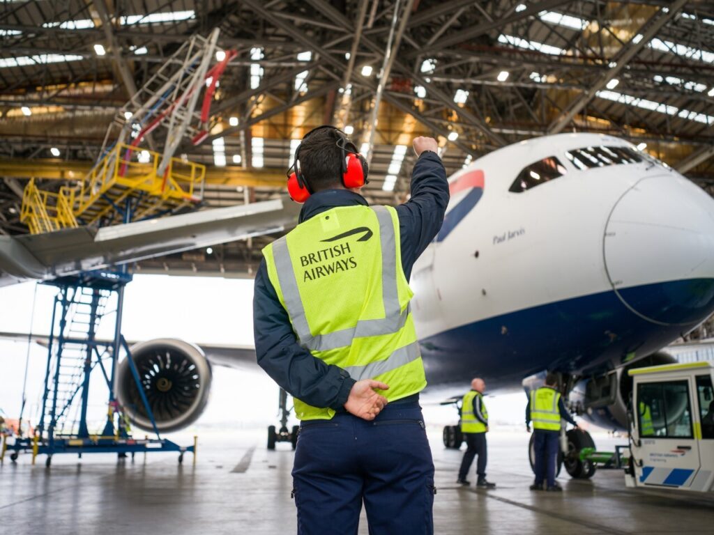 Ground handler monitoring a 787 being pulled into the hangar for the Starlink installation