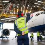 Ground handler monitoring a 787 being pulled into the hangar for the Starlink installation