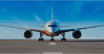 nose-on view of a 787 on the ramp with blue skies behind.