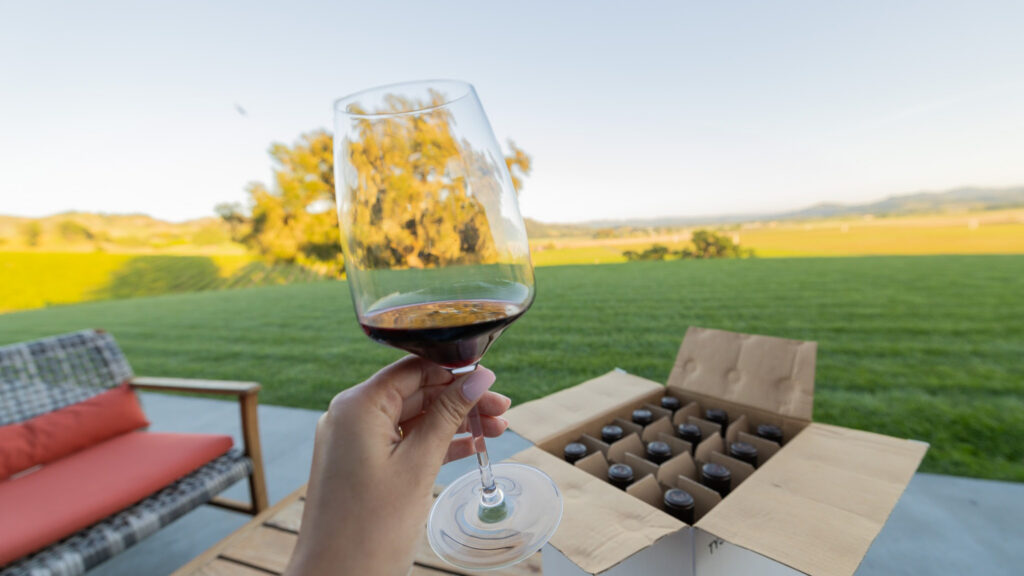 Sipping a glass while looking at a case of wine and a wide horizon at a putative vineyard. That box of wine will check free, after being repacked, as part of the new Southwest Airlines Sip and Ship program.