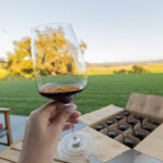 Sipping a glass while looking at a case of wine and a wide horizon at a putative vineyard. That box of wine will check free, after being repacked, as part of the new Southwest Airlines Sip and Ship program.