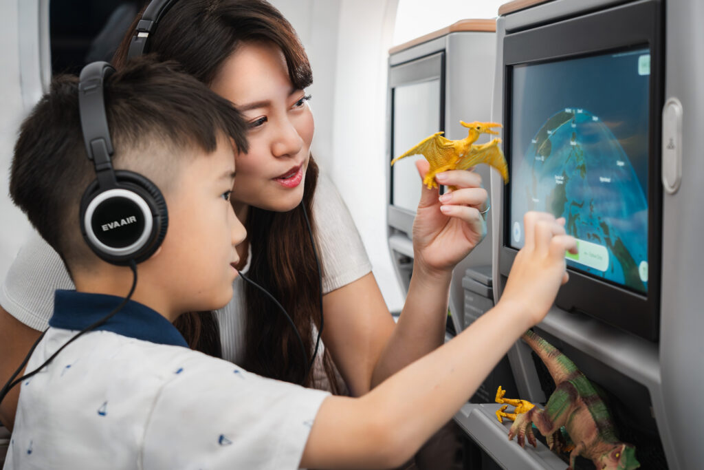 Kid playing with the inflight map while mom holds a dinosaur toy to demonstrate that the map - which isn't really visible - is kid-friendly.