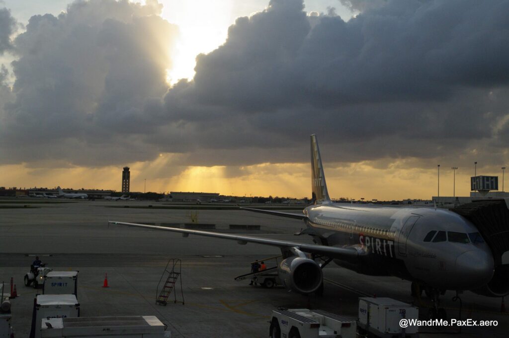 clouds and sunset over a Spirit A320 with the black and white checkered tail livery