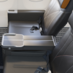 Rendering of the new Allegiant First seats, mostly grey with orange highlights and the company's sunburst logo embossed on the headrest.