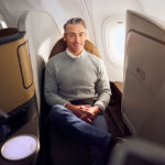 Guy sitting in a narrow business class seat on a plane