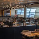 Mostly empty airport lounge with lots of seats and a bar and fancy lights and such.