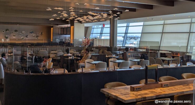 Mostly empty airport lounge with lots of seats and a bar and fancy lights and such.