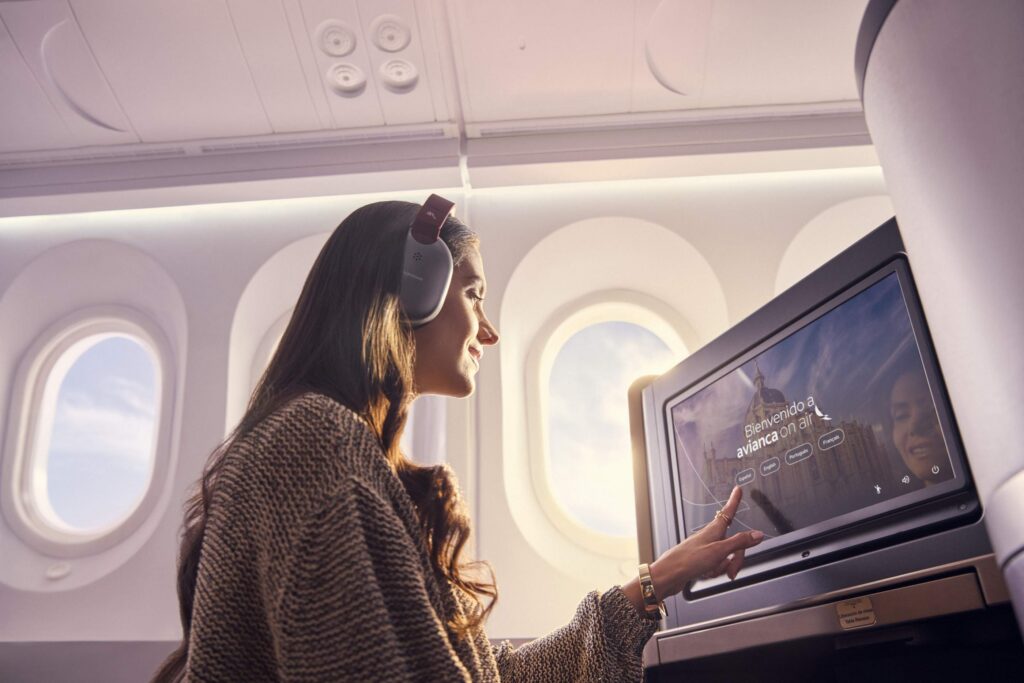 woman using a large IFE screen in an airplane seat