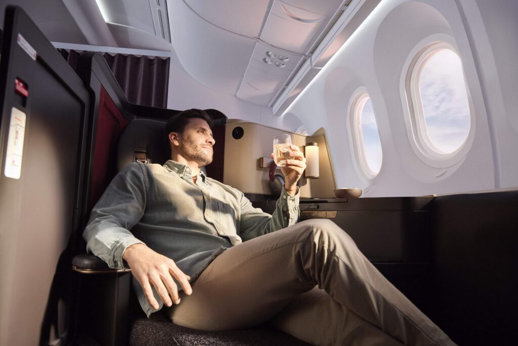 Guy relaxing while holding a drink in a business class seat